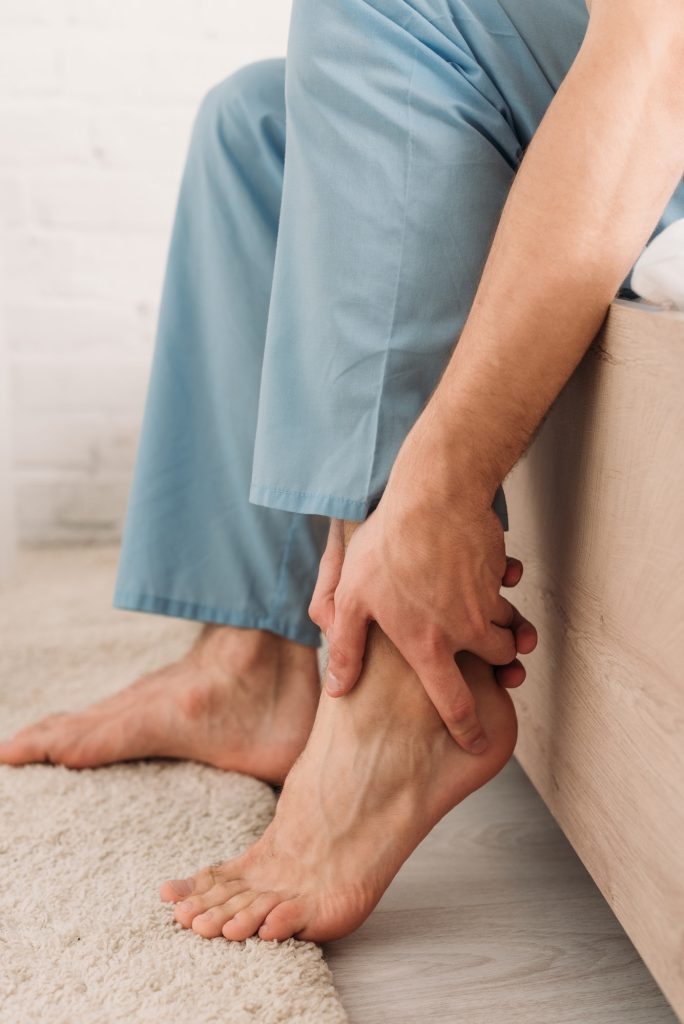 cropped view of man touching leg while suffering from pain in Achilles tendon